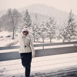 Woman standing on snow covered tree against sky