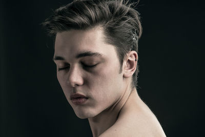 Close-up of young man against black background