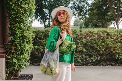 Portrait of a young woman holding a mesh bag with veggies on her shoulder 