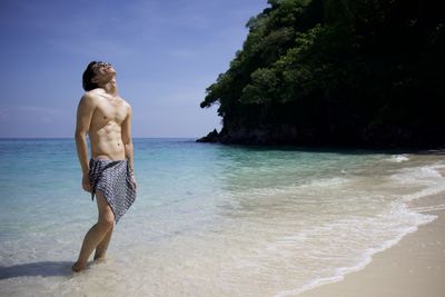 Full length of shirtless man standing on beach