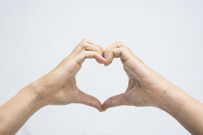 Close-up of hand holding heart shape over white background