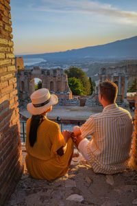 Rear view of people sitting on terrace against sky