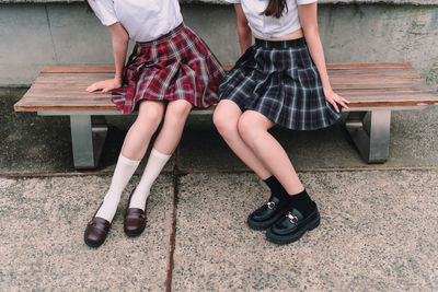 Low section of women sitting on bench