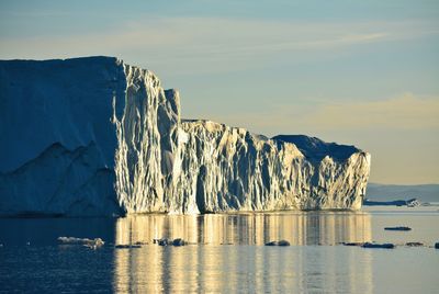 Boat trip at midnight sun, wonderful yellow icebergs in the arctic sea in north greenland icefjord