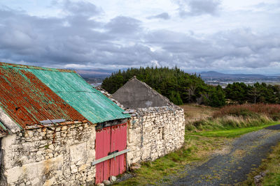 House on field by road against sky