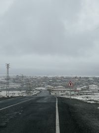 Road passing through city against sky