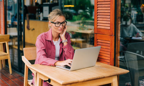 Young beautiful smart business woman working on laptop in coffee shop.