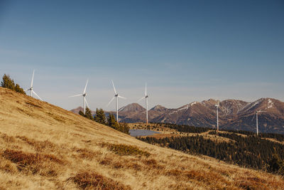 Wind turbines on field against sky