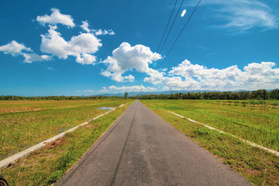 Road amidst field against sky