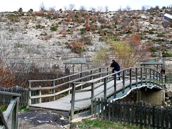 Man on footbridge against sky