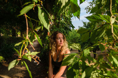 Portrait of young woman standing against plants