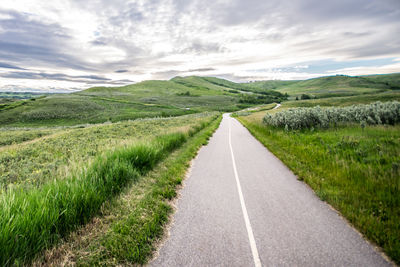 Road amidst field against sky