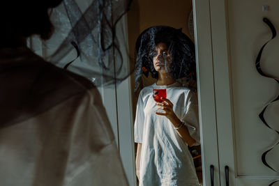 One girl with a red halloween drink is reflected in the mirror.