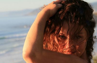 Close-up portrait of young woman against sea