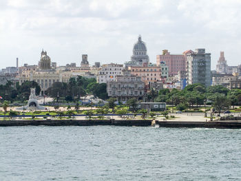 City at waterfront against cloudy sky