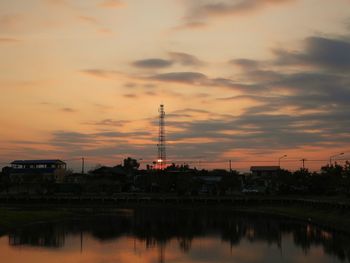 Silhouette trees by electricity pylon against sky during sunset