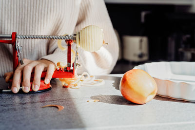 Close up of girl hands slicing apple using slicer machine. child cooking charlotte or apple pie