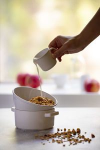 Midsection of person holding ice cream in bowl on table