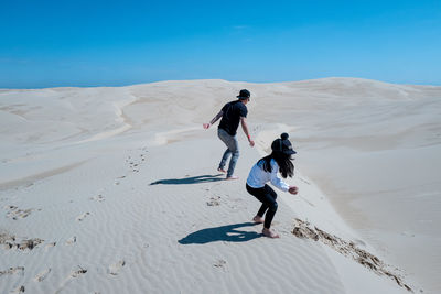 Father and daughter playing with sand in desert