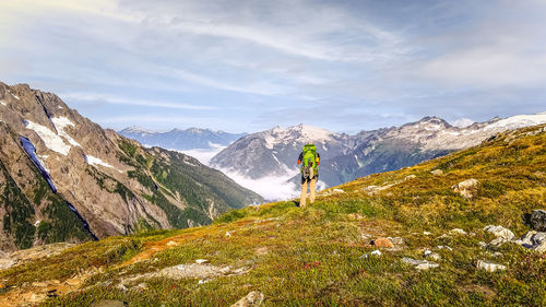 Rear view of man walking on mountain against sky