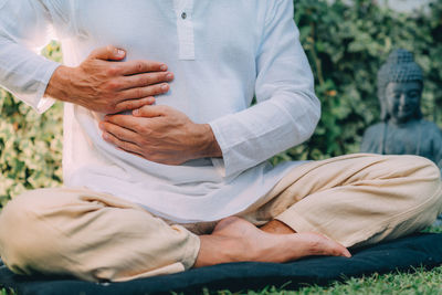 Male therapist performing reiki therapy self treatment holding hands over his stomach