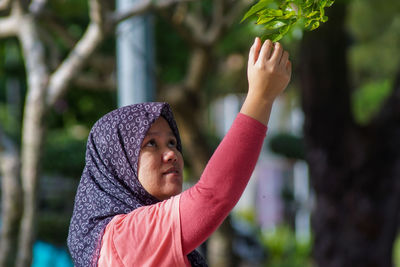 Close-up of woman wearing hijab touching leaves