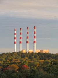 Built structure by factory against sky during sunset