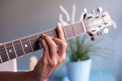 Cropped hand playing guitar at home