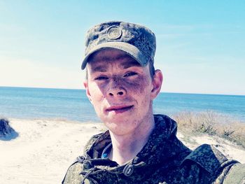 Portrait of smiling man standing at beach against clear sky