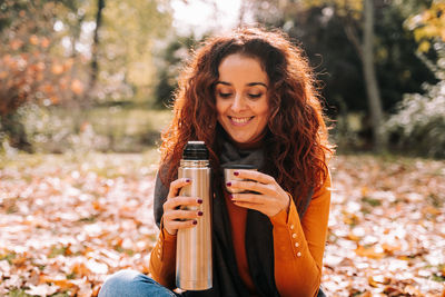 Portrait of a smiling young woman drinking coffee outdoors