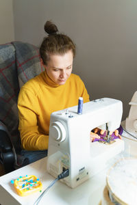 Focused woman seamstress using sewing machine at her creative workspace at home