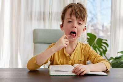 Bored little student yawning during reading at home