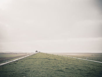 Road amidst agricultural field against sky