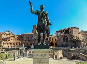 Statue in city against clear blue sky