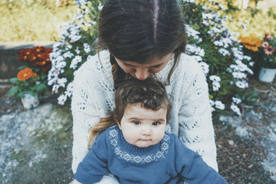 Portrait of cute baby sitting with mother outdoors