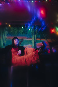 Portrait of woman sitting in illuminated nightclub