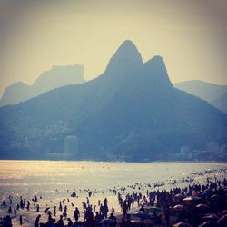 People on beach against mountains