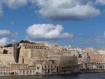 Buildings in city against cloudy sky