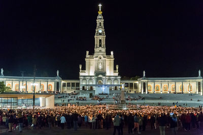 Crowd at illuminated temple against sky at night