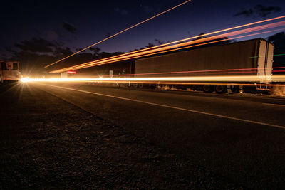 Light trails on road against sky at night