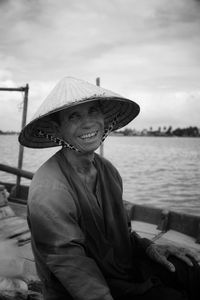 Portrait of smiling woman wearing hat against sea
