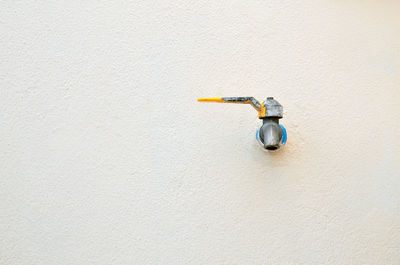 Close-up of white faucet in bottle against wall