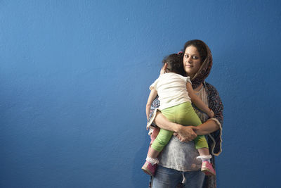 Full length of woman standing against blue wall