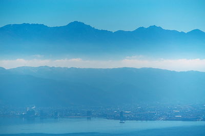 Scenic view of sea and mountains against blue sky