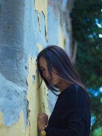 Portrait of woman standing against wall
