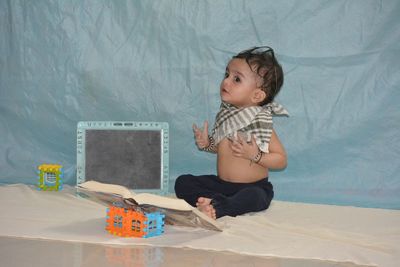 Cute boy sitting on bed at home