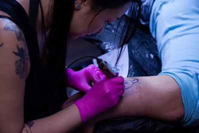 Woman tattooing on man arm at studio