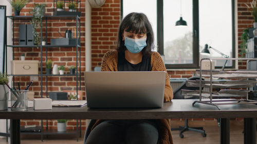 Businesswoman wearing mask using laptop