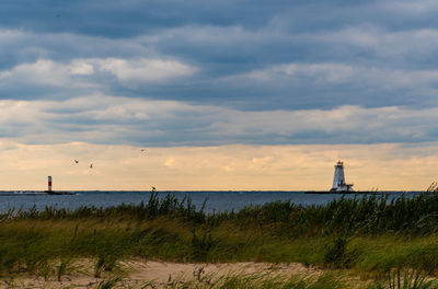 Lighthouse by sea against sky