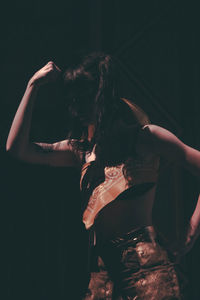 Rear view of woman standing against black background